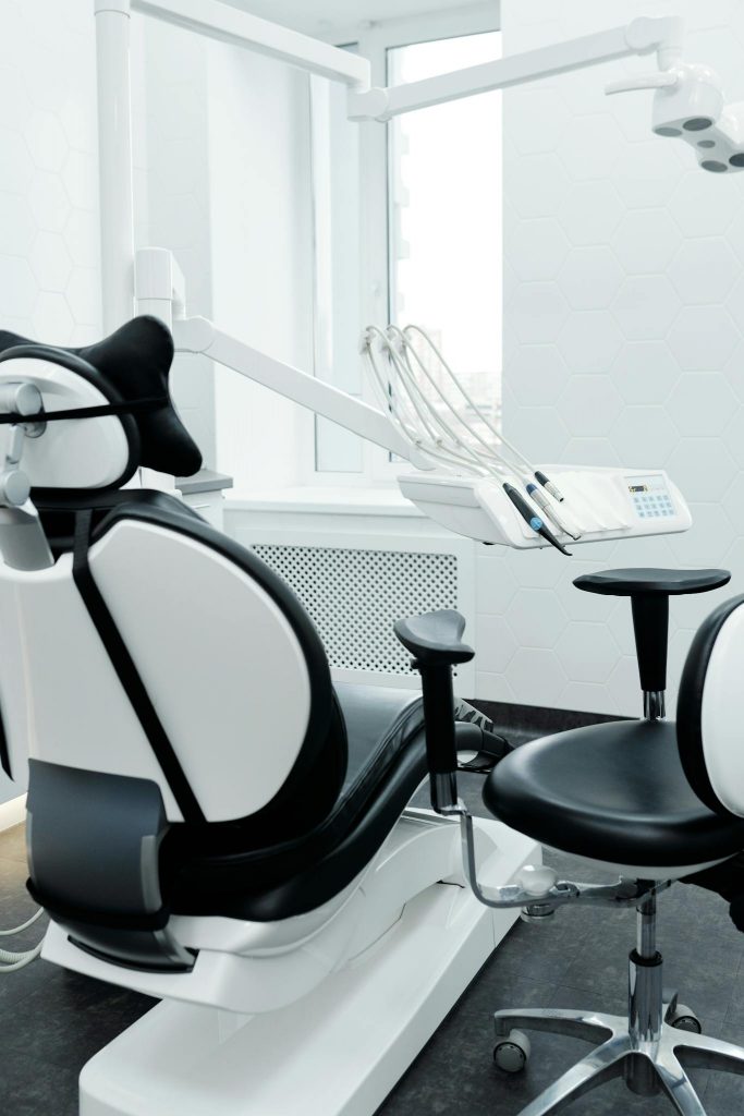 A modern dental chair and equipment setup in a bright, clean dental clinic.