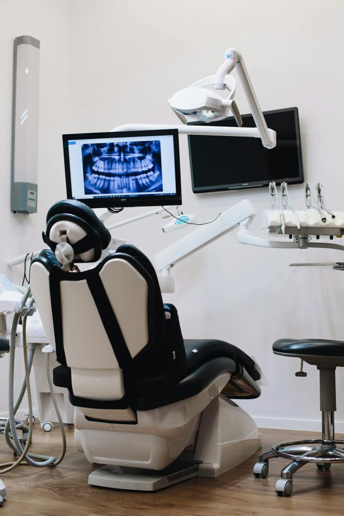 A modern dental clinic featuring a dental chair and equipment with an x-ray monitor display.