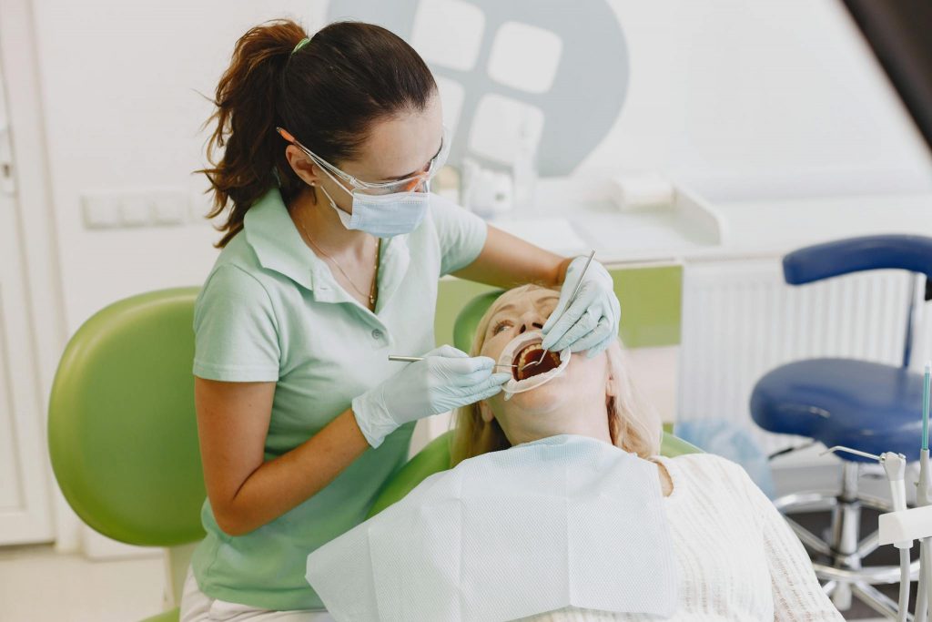 Dentist in mask examining a patient's teeth in a modern clinic setting.