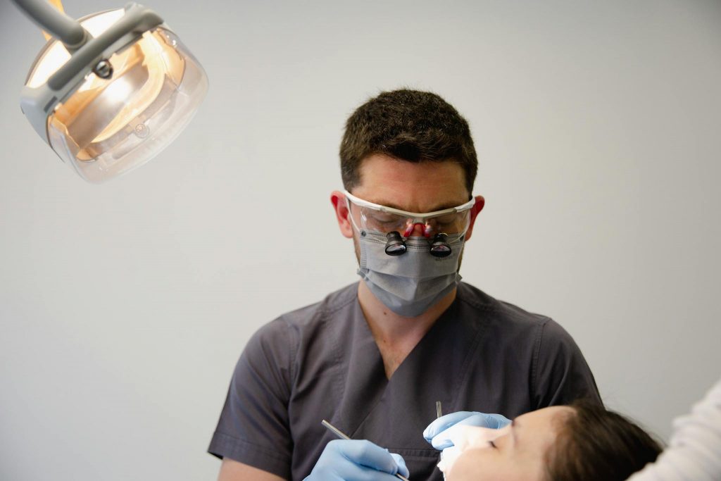 A dentist uses professional tools to treat a patient in a well-lit dental office.